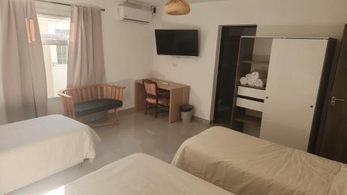 a room with two beds and a desk and a television at Itzel in Picún Leufú