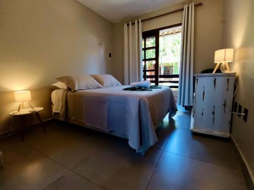 una camera da letto con un letto, due lampade e una finestra di Colibri - Conforto e Vista-Mar no Coração de Pipa a Pipa