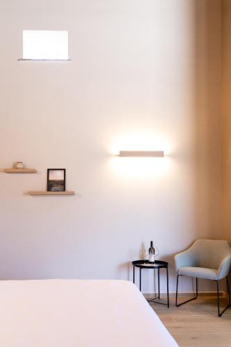 a bedroom with a white bed and a chair at RESPIRA - rooms & apartments in Serralunga d'Alba