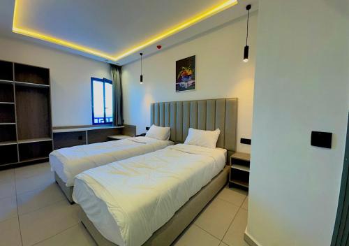 a bedroom with two beds with white sheets at Hôtel Fnideq Senator in Fnidek