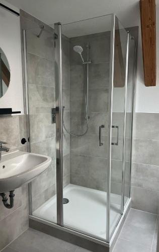 a shower with a glass door next to a sink at studio lb 11 Moderne, helle Dachwohnung am Rande der Schwäbischen Alb in Bartholomä
