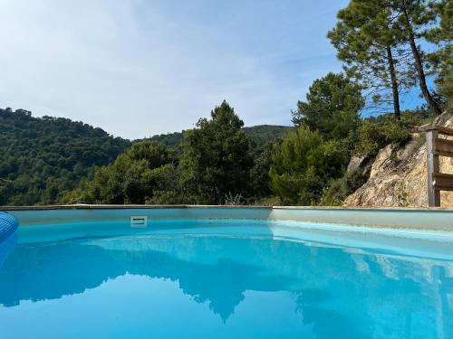a swimming pool with blue water and mountains in the background at Maison du soleil in Mérindol-les-Oliviers