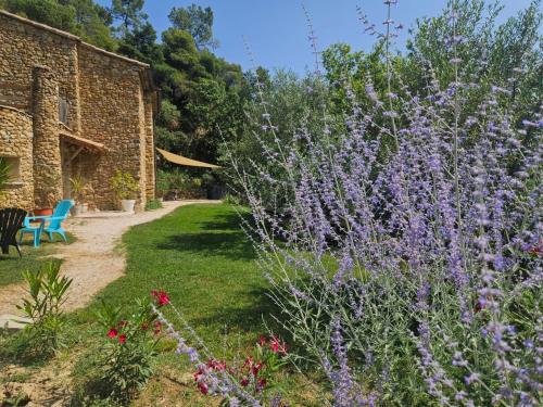a garden with purple flowers next to a brick building at Maison du soleil in Mérindol-les-Oliviers