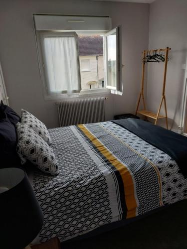 a bed in a bedroom with a window and a bedspread at Chez Marie Claude in Le Mans