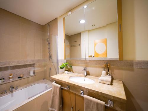 a bathroom with a sink and a tub and a mirror at Luxury Cozy Minimalist 1BR Haven Connected to Dubai Mall in Sabkhah