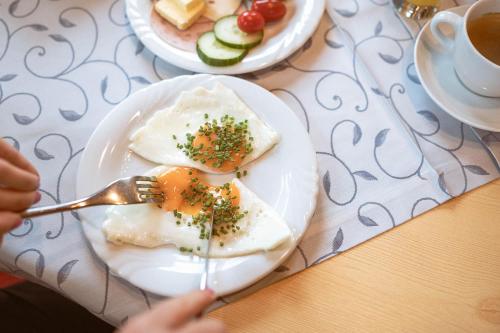 a person eating eggs on a plate with a fork at Hotel Bachschmied in Maria Alm am Steinernen Meer