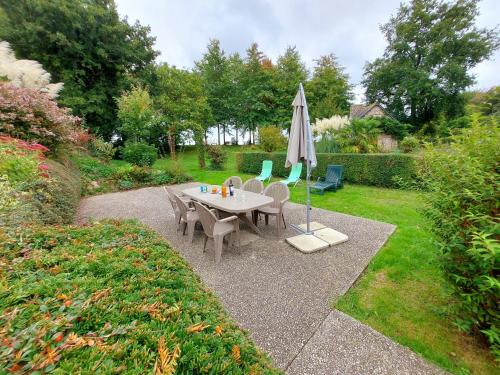 a table and chairs and an umbrella in a garden at Lusachères in La Pellerine
