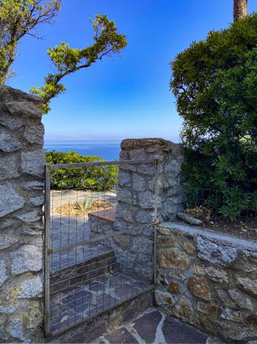 a gate in a stone wall with the ocean in the background at Residence Intur in Marciana Marina