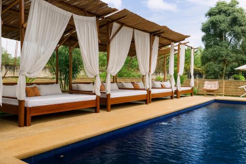 a group of beds under a pavilion next to a pool at On Board Lifestyle Resort FREE MOTORBIKE in Bil-isan