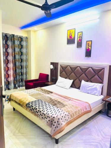 a bedroom with a large bed and a red chair at Hotel Heaven in Rohtak