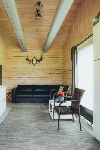 a living room with a black couch and chairs at Dūjas in Duķuri
