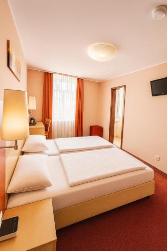 a hotel room with a large bed and a desk at Atomis Hotel Düsseldorf City in Düsseldorf