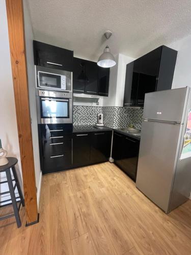une cuisine avec des armoires noires et un réfrigérateur en acier inoxydable dans l'établissement Laetitia Touzé, à Rennes