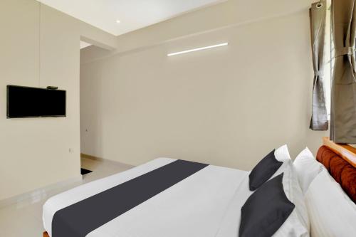 a bedroom with a bed and a tv on a wall at Super Collection O Lefort LUXE by PopTavern in Trivandrum