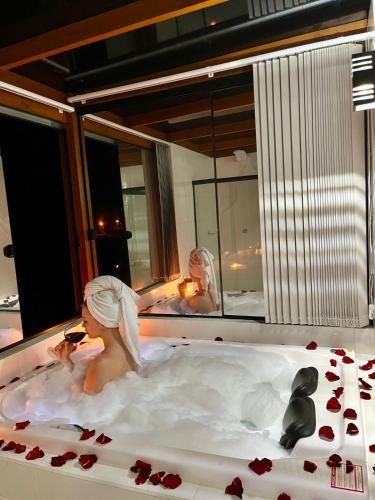 a woman taking a picture in a bath tub at Chalé Dovale in Sambaqui