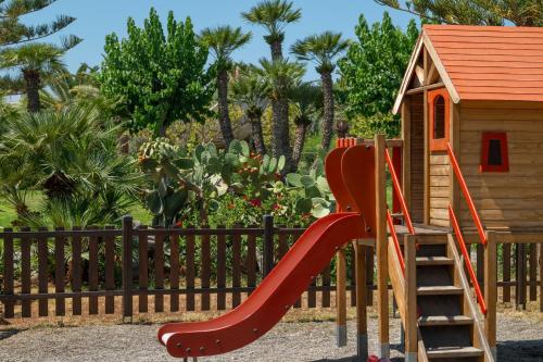 a playground with a red slide next to a house at Iberostar Waves Creta Panorama & Mare in Panormos Rethymno