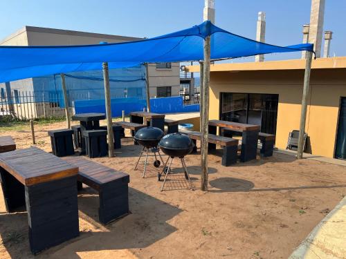 a grill and picnic tables with a blue tent at Beachfront Hotel, La Mercy in Umhlanga