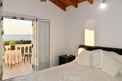a bedroom with a bed and a balcony with the ocean at Barbara's Beach House in Lefkímmi