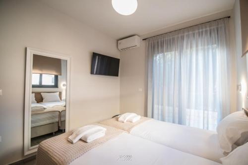 a hotel room with two beds and a mirror at Gialos Villas Paleochora in Palaiochóra