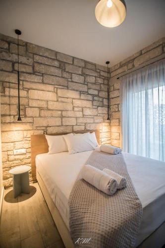 a bedroom with a large bed and a brick wall at Gialos Villas Paleochora in Palaiochóra