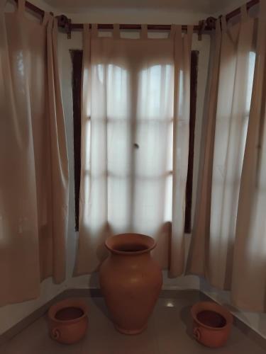 a vase and two pots in front of a window at Alquiler Temporal Ñuca huasi in Salta