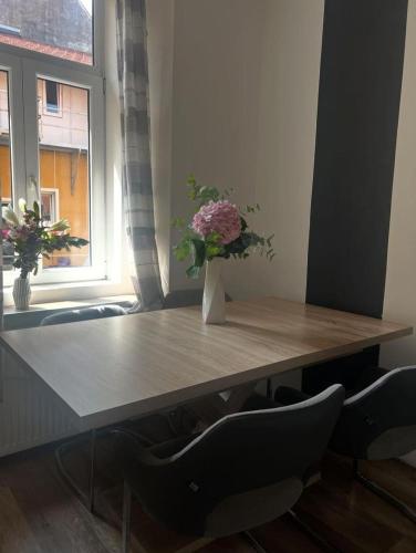 a wooden table with a vase of flowers on it at City soul duplex apartment in Maribor