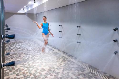 a woman in a blue bathing suit walking in a bathroom at SERHS Experience Suítes in Natal