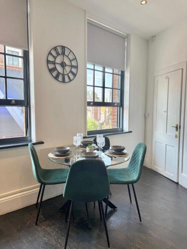 a dining room with a table and chairs and a clock at Modern 1-Bedroom Apartments near Shoreditch, Old Street & Hoxton by NourNest Apartments in London