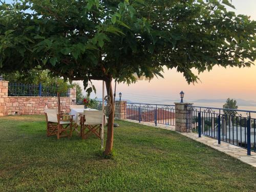 una mesa y sillas bajo un árbol junto a una valla en Akritochori house with great view, en Akritokhórion