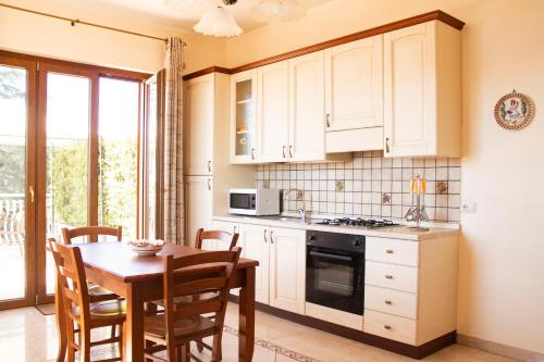 a kitchen with white cabinets and a table with chairs at Etna Royal View in Trecastagni