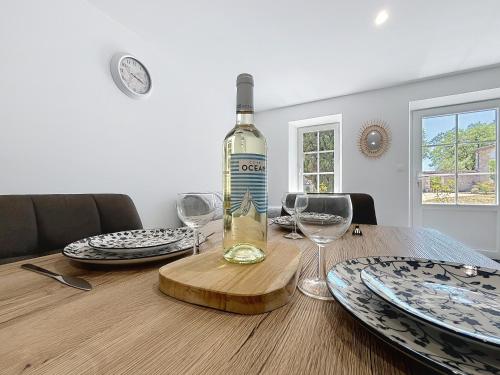 a bottle of wine sitting on a table with glasses at Hortensia - 2 chambres - Charme et Calme au cœur du Blayais in Anglade