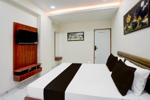 a bedroom with a large white bed with black pillows at Hotel O Railway in Vadodara