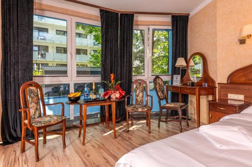 a hotel room with a table and chairs and a window at Apartamenty BLACK PEARL in Kołobrzeg