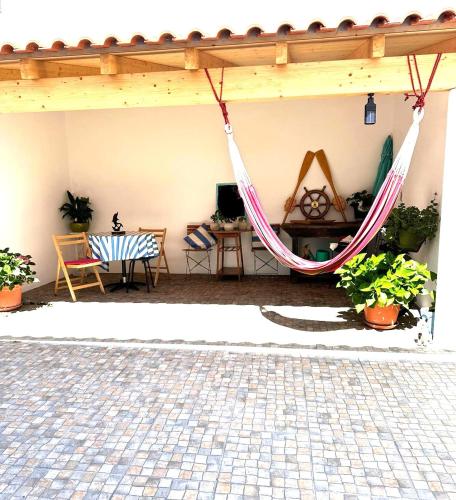 a hammock in a patio with a table and chairs at CASA DAS MARÉS MILFONTES by Stay in Alentejo in Vila Nova de Milfontes