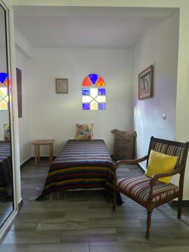a room with a bed and a chair and a window at Domaine des Mimosas in Essaouira