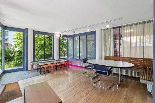 a room with a table and chairs and windows at A & G Rooms Self Check-In in Zürich