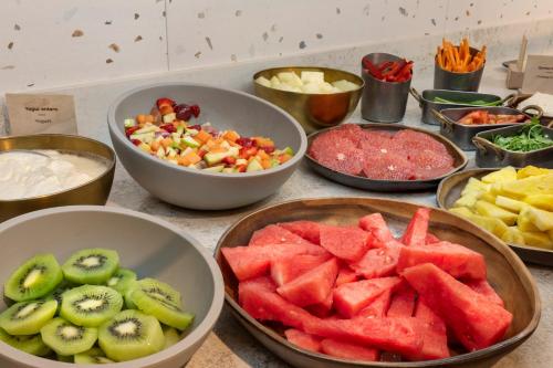 a table topped with bowls of fruits and vegetables at Catalonia Excelsior in Valencia