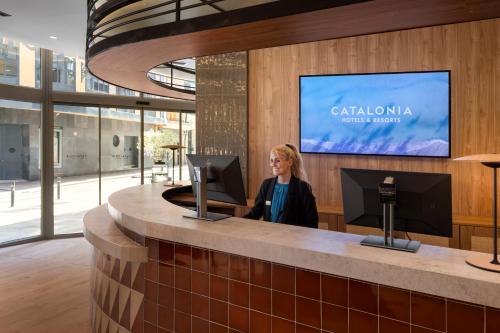 a woman standing at a counter in a lobby at Catalonia Excelsior in Valencia