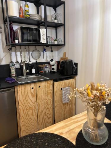 a kitchen with a sink and a table with a vase of flowers at Eden Studio in Ajaccio