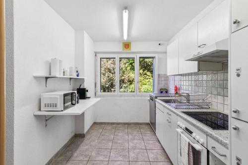 a white kitchen with a microwave and a window at A & G Rooms Self Check-In in Zürich