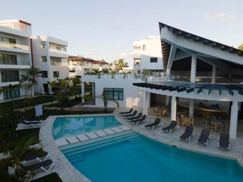 a swimming pool with chairs and a building at Beachfront penthouse - Amar'e Aparthotel & Spa in Las Terrenas