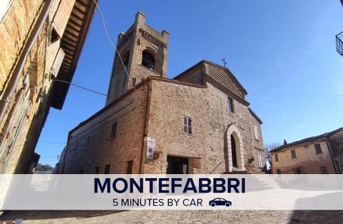 an old brick building with a clock tower on it at Casetta in collina 4 in Colbordolo