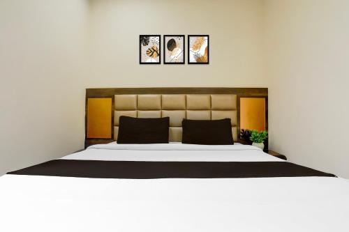a bedroom with a large white bed with three pictures on the wall at SPOT ON Hotel Center Point Inn in Bhilai