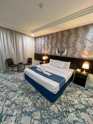 a hotel room with a large bed and two chairs at فندق اركان المطاف توصيل مجاني للحرم in Makkah