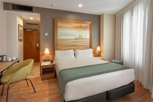 a hotel room with a large bed and a desk at Catalonia Excelsior in Valencia