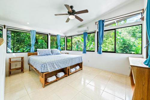 a bedroom with a bed with blue curtains and windows at Sea View Modern dream House in Pavones
