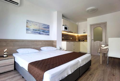 a bedroom with a large bed and a kitchen at Cabacum Pleasure Beachfront Apartments in Varna City
