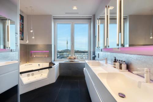 Un baño con dos lavabos y una gran ventana. en Munichs No1 Luxury Sky Terrace Penthouse with Unlimited Panoramic City and Alps Views, en Múnich