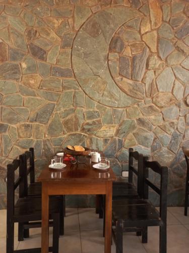 a wooden table with chairs in front of a stone wall at Hostal Inti Urubamba in Urubamba