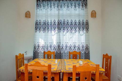ein Esszimmer mit Tisch, Stühlen und einem Vorhang in der Unterkunft SG House in Paje